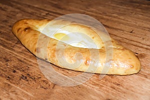 Hachapuri on Adjara open pie with egg on wooden background