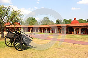 Hacienda colonnial country house, stone construction arches and wooden cart on the lawn photo