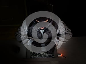 Hacker with balaclava typing on laptop