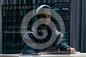 Hacker in black hood and computer trying to carry out a cyberattack over the internet