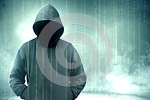 Hacker in black hoodie standing with binary code on virtual screen