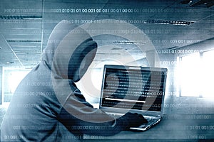 Hacker in black hoodie using laptop on the desk to hacking system with binary code and upload the malware