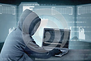 Hacker in black hoodie using laptop on the desk to hacking system with binary code and upload the malware