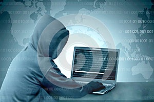 Hacker in black hoodie using laptop on the desk to hacking system with binary code and upload the malware