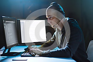 Hacker with computer and headset in dark room