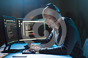 Hacker with computer and headset in dark room