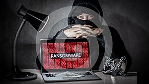 Hacker with computer screen showing ransomware attacking