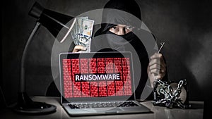 Hacker with computer screen showing ransomware attacking photo