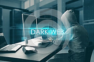 Hacker at desktop using computers with abstract creative digital text hologram on blurry office interior background. Dark web,
