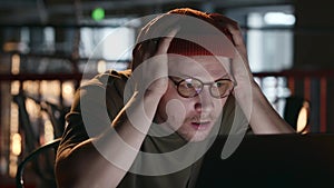 a hacker with glasses grabs his head with his hands and looks very surprised
