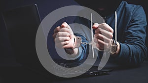 Hacker in handcuffs with laptop. Cyber crime