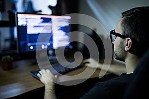 hacker in headset and eyeglasses with keyboard hacking computer system