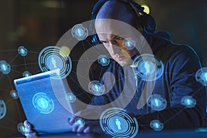 Hacker in headset typing on laptop in dark room