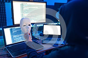 Hacker in hood holds mask in hand, crime lifestyle