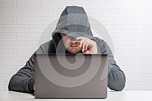 A hacker in a hood with a laptop steals data