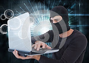 Hacker with hood using a laptop in front of digital background