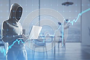 Hacker in hoodie using laptop with growing blue financial forex chart on blurry office interior background. Stock, economy,