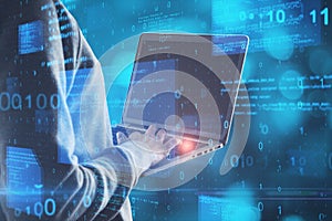 Hacker in hoodie using notebook with abstract glowing blue coding background. Binary code, theft, technology, data and internet