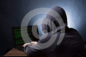 Hacker with laptop initiating cyber attack