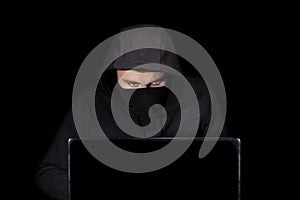 Hacker with laptop initiating cyber attack,  on black