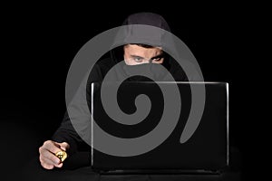 Hacker with laptop initiating cyber attack,  on black
