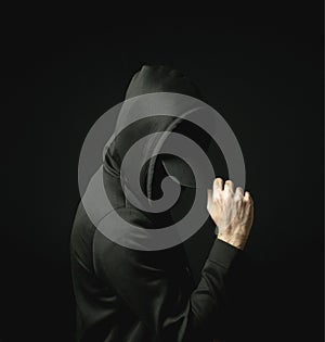 Hacker Man in black hat and hoodie in the dark alone