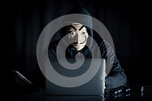 Hacker man in mystery mask using laptop
