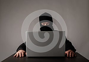 Hacker in mask using a laptop