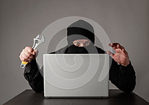 Hacker in mask using a laptop
