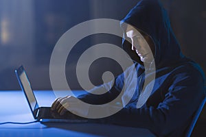 Hacker with microphone and laptop in dark room