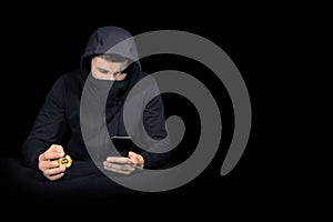 Hacker with mobile phone and bitcoin initiating cyber attack,  on black