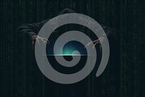 hacker over a screen green binary code. Crime and Information Theft and Computers