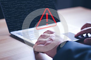 Hacker or programmer using laptop with triangle caution warning sign, coding, cryptography, hacker, crime, virus, for notification