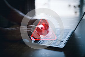 Hacker or programmer using laptop with triangle caution warning sign, coding, cryptography, hacker, crime, virus