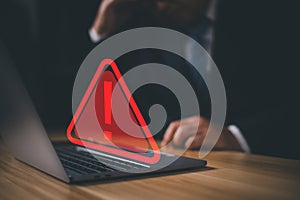 Hacker or programmer using laptop with triangle caution warning sign, coding, cryptography, hacker, crime, virus,