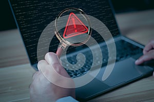 Hacker or programmer using laptop with triangle caution warning sign, coding, cryptography