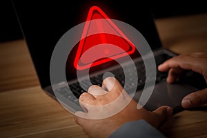 Hacker or programmer using laptop with triangle caution warning sign, coding, cryptography