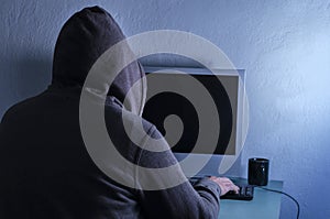 Hacker`s back who sitting against screen and hacking the system in the office