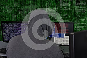 A hacker sits behind computer monitors on an abstract background, attacking and hacking servers with a virus. Creation and dissemi