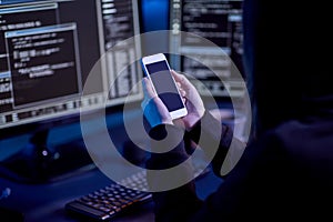 hacker with smartphone and computers in dark room