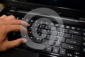 Hacker typing code on laptop keyboard with his fingers photo