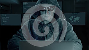 Hacker typing at laptop. Man coding on computer dark night. Man in dark glasses coughs.