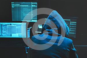 Hacker using computer for organizing massive data breach attack on goverment servers. Hacker in dark room surrounded
