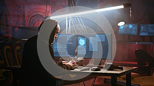 Hacker using computer to run malicious code in foggy dark basement