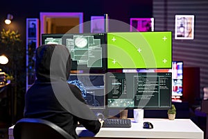 Hacker using green screen PC, coding malware designed to exploit backdoors