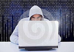 Hacker using a laptop in front of digital screen
