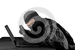 Hacker using magnifying glass on a laptop computer