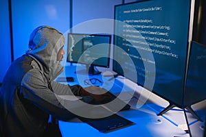 African american Hacker Using Multiple Computers For Stealing Data On Desk