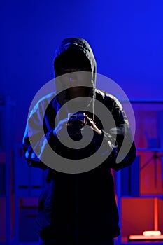 Hacker using smartphone for phishing attack and data theft in dark cyber environment