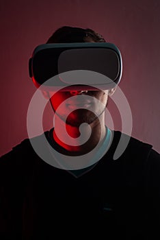 A hacker in the VR glasses in red light, the gamer in the virtual space